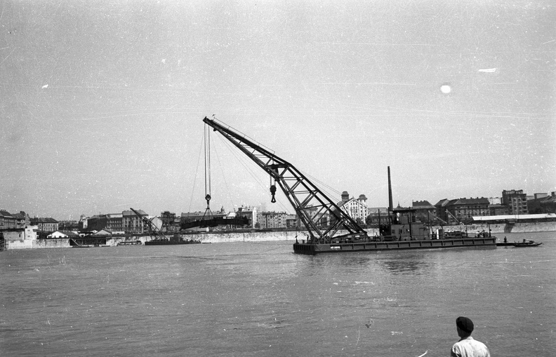 az Ady Endre úszódaru a Petőfi híd elemét szállítja az építkezés helyszínére, háttérben a Soroksári út épületei.